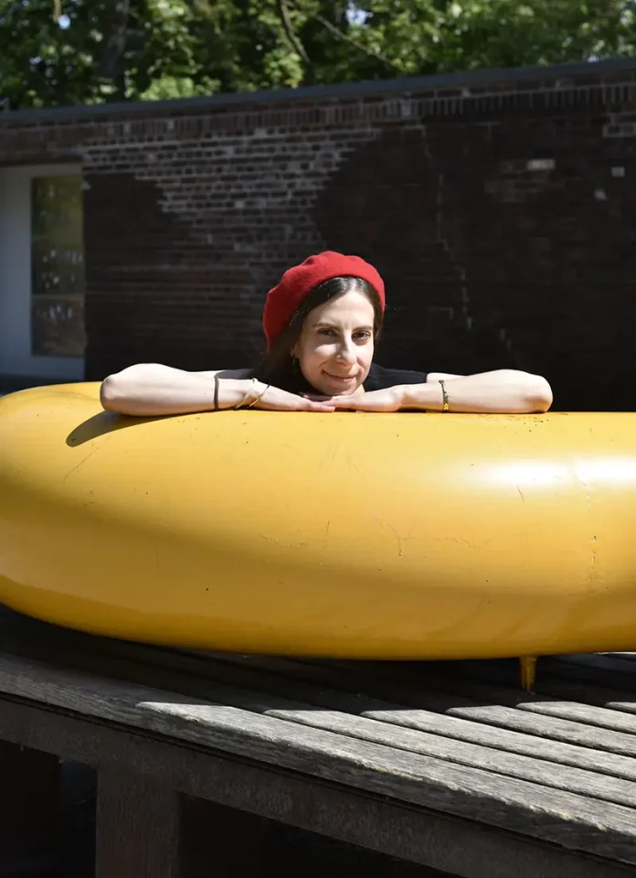Designerin Giulia Cappello lehnt sich auf eine abstrakte gelbe Skulptur